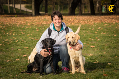 Piros két kutyával az oldalán mosolyog