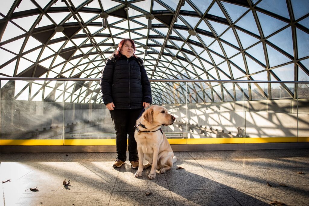 Dóri and Noé standing under a modern glass dome ceiling- in the Bálna, Budapet.