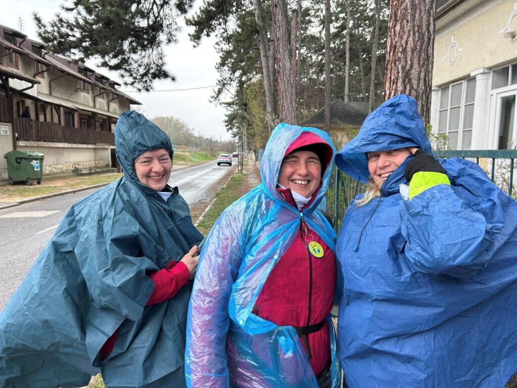 A képen középen Borsodi Erzsébet látható, mellette két kísérője, mindhárman esőkabátban vannak.